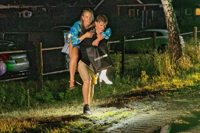 Een jongeman brengt een jongedame in veiligheid. 