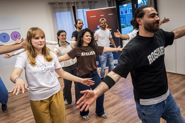 Begeleidster Ayşe Oral (midden, bruin shirt) danst met de gevluchte jongeren. Links naast haar (in gele broek) Polina uit Oekraïne.