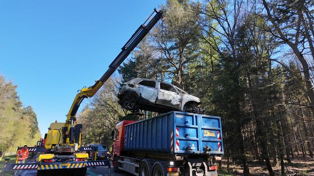 De uitgebrande elektrische auto wordt in een dompelbak getakeld.