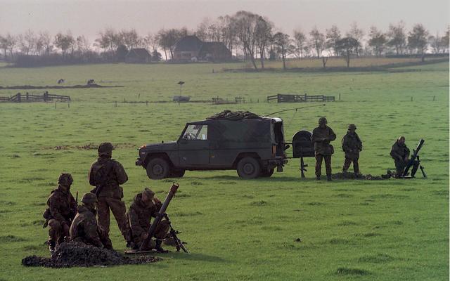 Militairen oefenen in een weiland.
