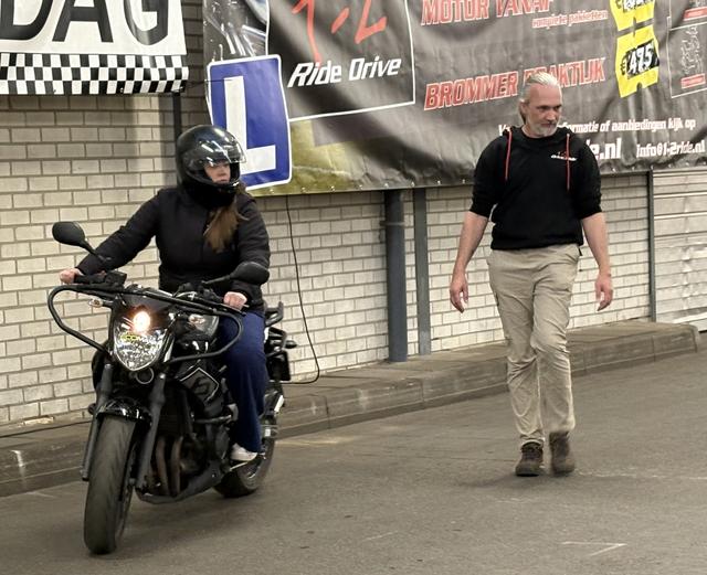 Een jongedame ervaart wat het is om voor het eerst op een motor te rijden. Met begeleiding van de rijschool.