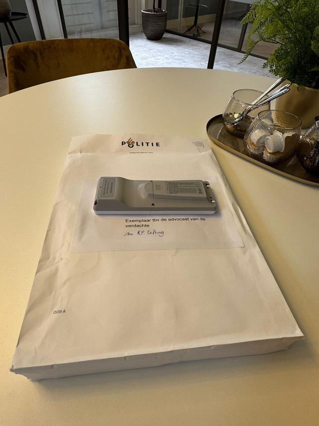 De witte enveloppe met stukken die advocaat Robert Eefting bezorgd kreeg. De telefoon op de stukken verbergt het adres.
