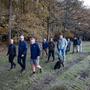 Menno Klok, vooraan met korte broek, wandelt met het behandelteam van zijn zoon in het bos bij Annen. Links zijn vrouw Gea.