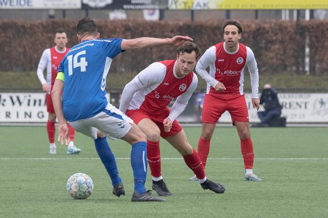 Yoran Popovic (midden het witrood van HZVV) en Lorenzo Valente (achtergrond) proberen Stefan Huiskes de bal te ontfutselen.