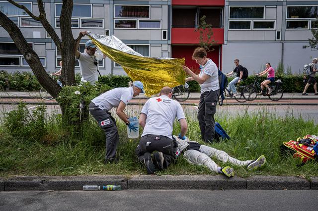 Medewerkers van het Rode Kruis ontfermen zich over een deelnemer die in het zicht van de finish door hitte is bevangen en niet meer verder kan.