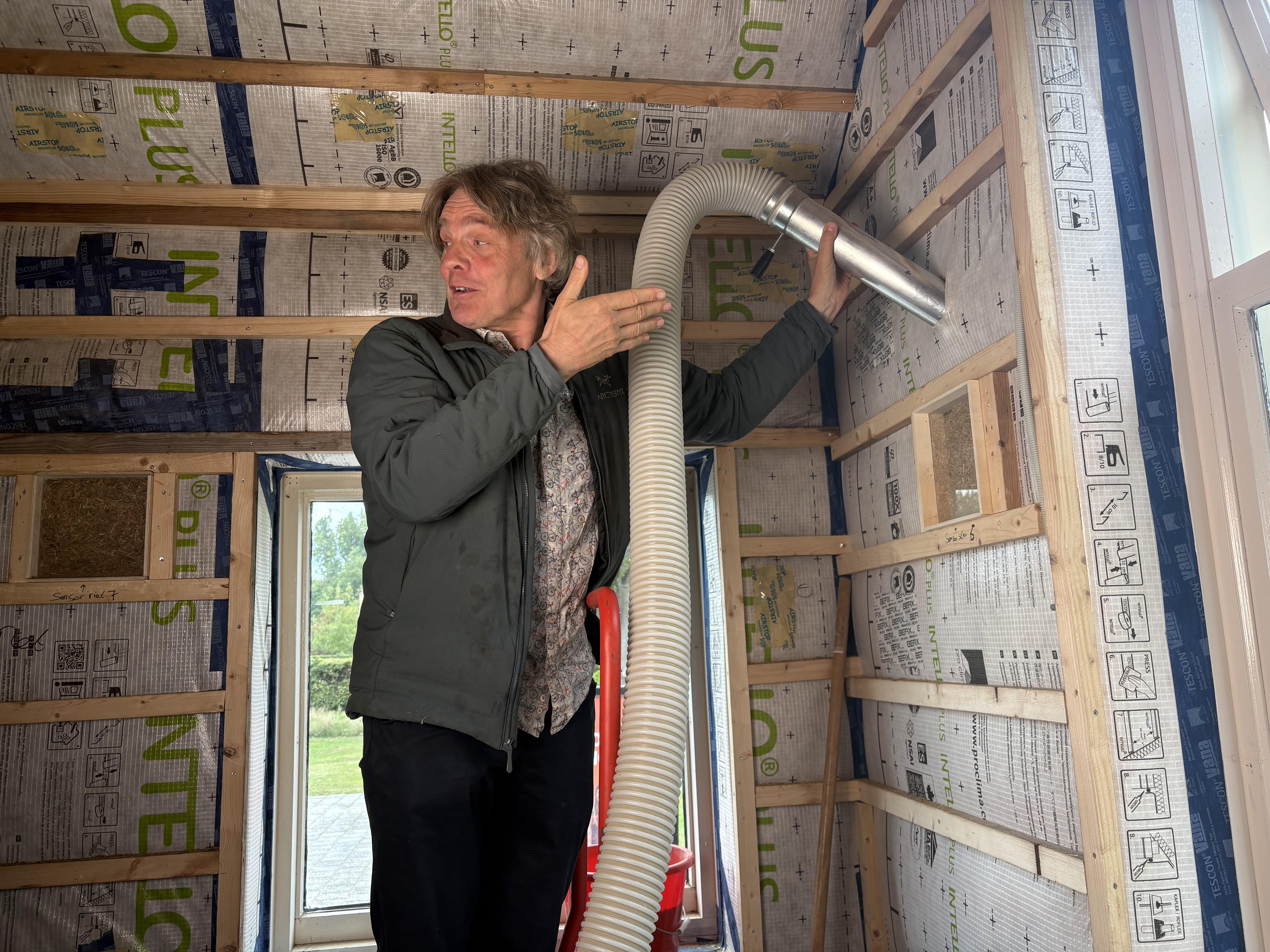 Wiebe Lamsma spuit het gehakselde stro van Freddy Oostra in de muren van de Versnellingshoeve. 