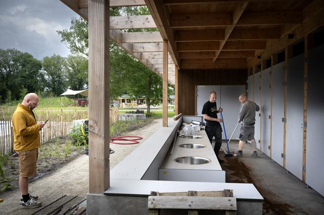 Er wordt hard gewerkt om De Kleine Wereld klaar te maken voor de ontvangst van gasten: Bas van Engeland (gele sweater) bij het gebouw met de sanitaire voorzieningen.