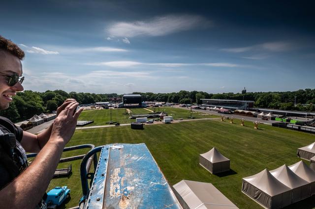 Op de drafbaan in het Stadspark wordt gewerkt aan het opbouwen van drie concerten. Vanuit een hoogwerker is heel het terrein te zien. 