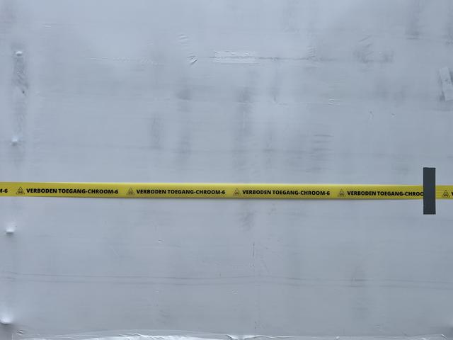 'Verboden toegang Chroom-6' staat op de linten rondom het ingepakte gebouw.