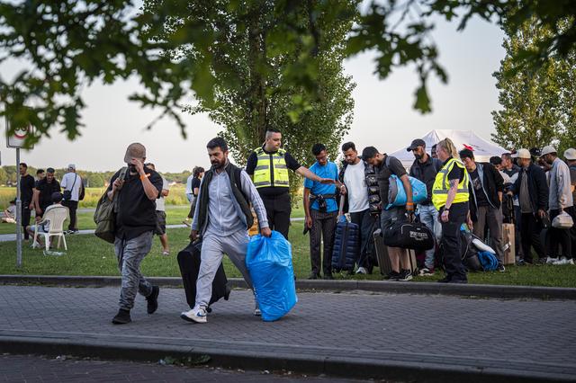 Asielzoekers worden bij het aanmeldcentrum, waar de opvanglocatie overvol is, opgehaald om de nacht elders door te brengen. 