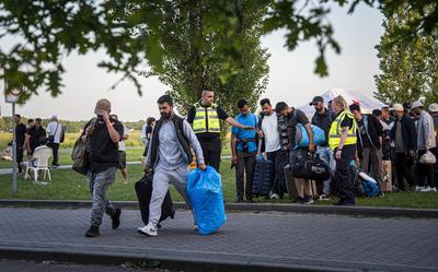 Asielzoekers worden bij het aanmeldcentrum, waar de opvanglocatie overvol is, opgehaald om de nacht elders door te brengen. 