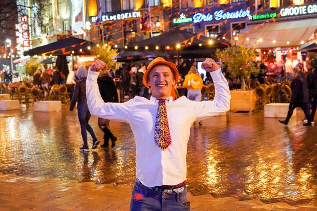 Een uitbundige jongen viert Koningsnacht op de Grote Markt in Groningen.