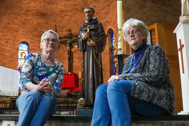 Willy Siekman (links) en Mia van Hebel naast het beeld  van Sint Franciscus, de heilige naar wie de kerk in Emmerschans is genoemd.
