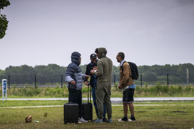 Asielzoekers staan klaar om in de bus te stappen die ze naar De Wijk brengt om daar te overnachten.
