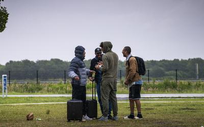 Asielzoekers staan klaar om in de bus te stappen die ze naar De Wijk brengt om daar te overnachten.