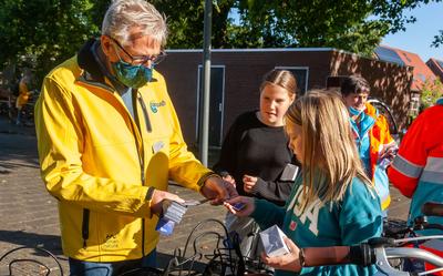 Anne-Marit Oosting (voorgrond) hangt samen met Bente Vliek en Fred van den Beemt 'geheugensteuntjes' aan de fietsen.