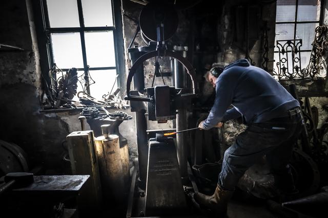 Een roodgloeiende ijzeren krul wordt bewerkt op de veenhamer.