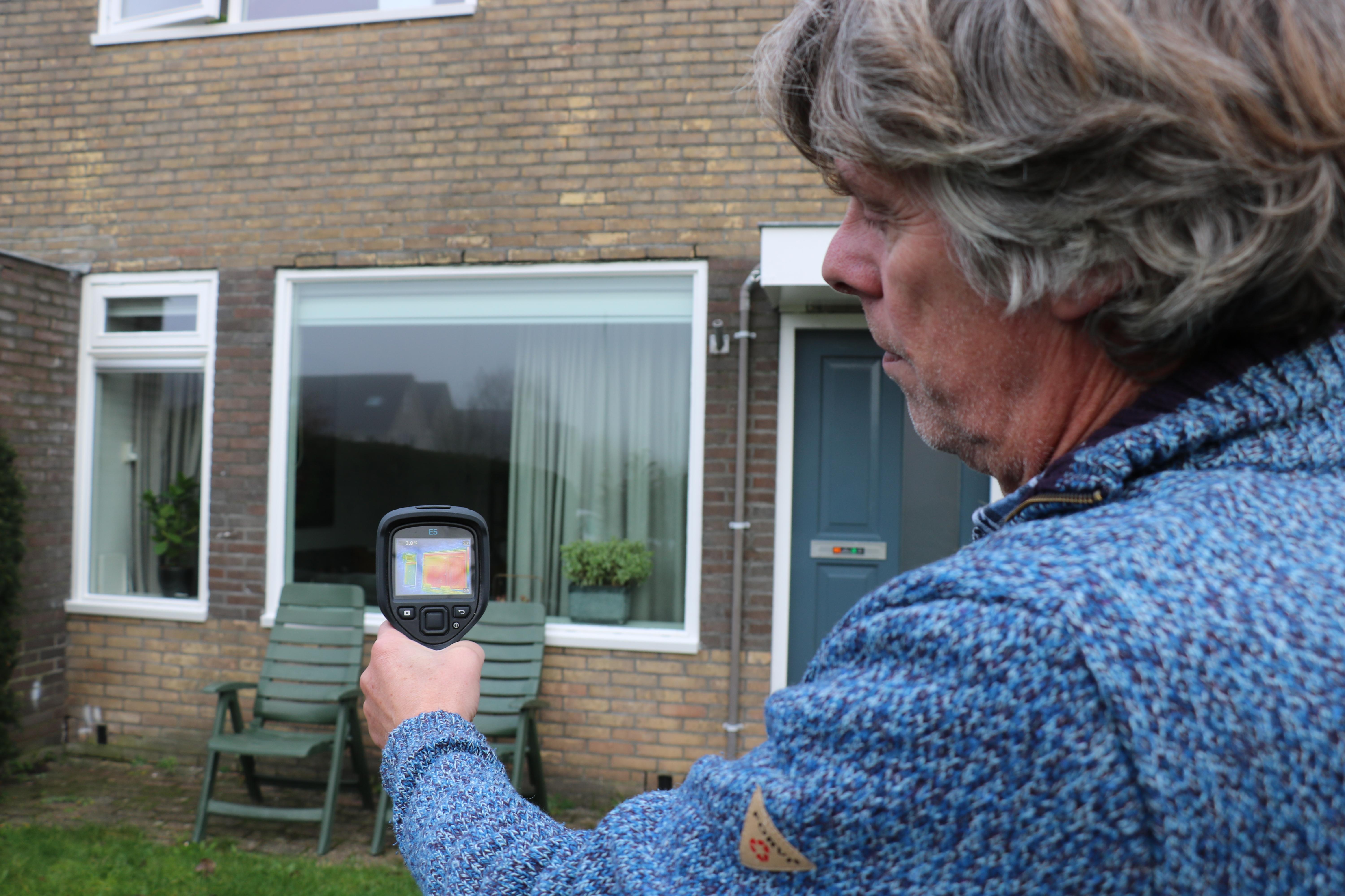 Hein Rumpt bekijkt de gevel met zijn warmtecamera. De meeste warmte lekt uit de ramen en deuren. 