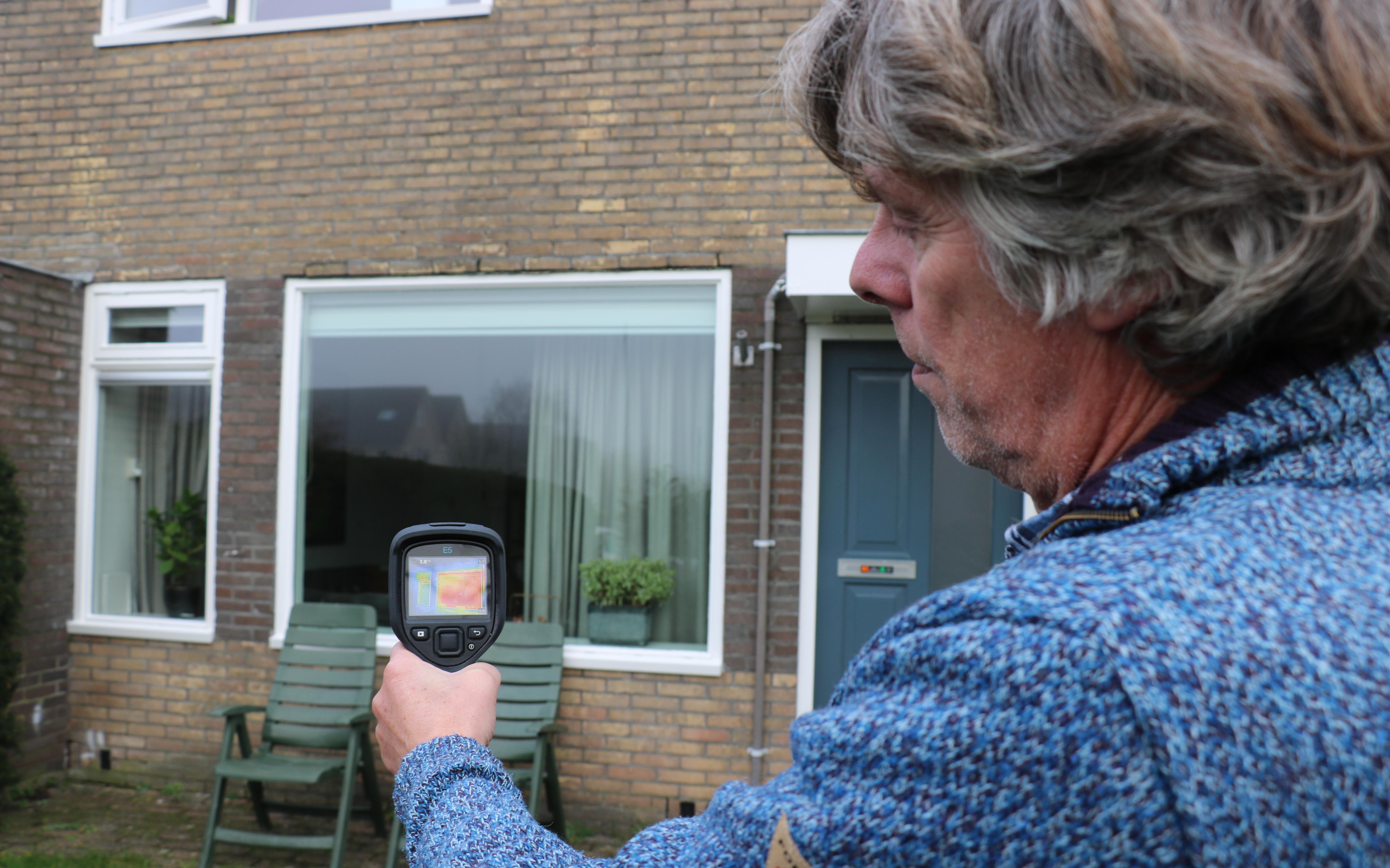 Hein Rumpt bekijkt de gevel met zijn warmtecamera. De meeste warmte lekt uit de ramen en deuren. 