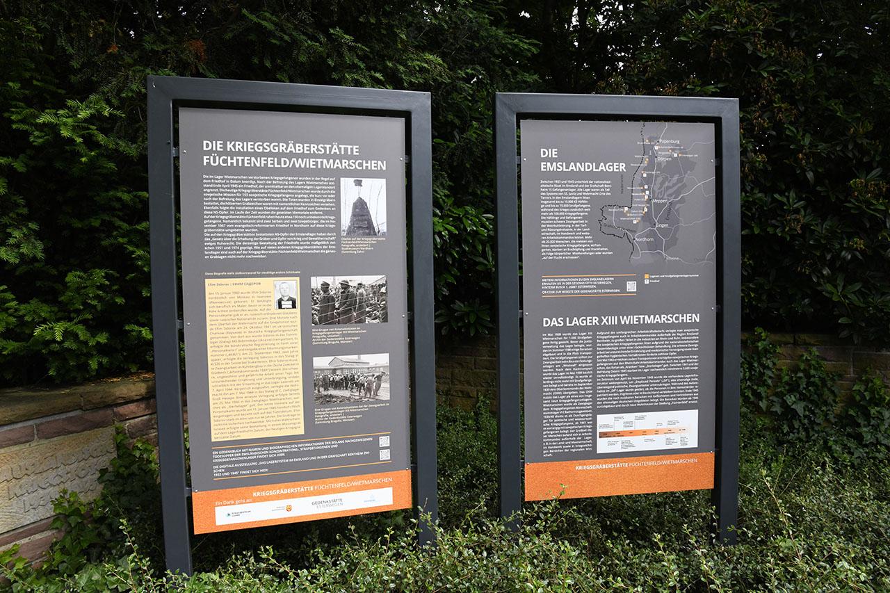 Op grote gedenkborden wordt de geschiedenis van de begraafplaatsen en kampen verteld.