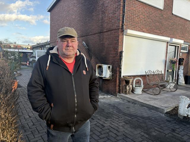 Martinus Bakker op de plek waar in de nacht van vrijdag op zaterdag zijn bestelbus in brand werd gestoken. Op achtergrond zijn woning.