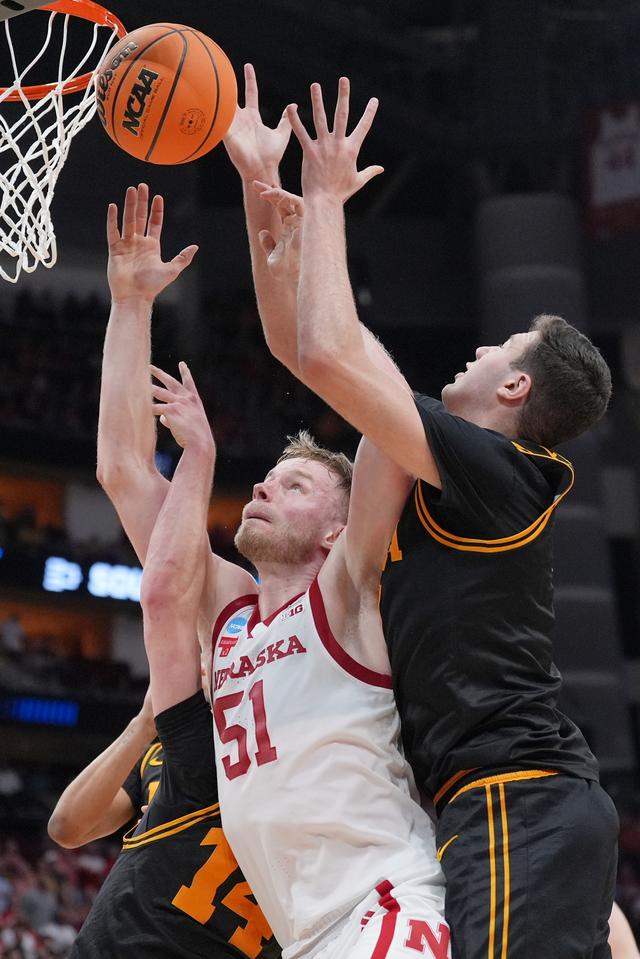 Rienk Mast van Nebraska onder de basket in gevecht met de bal met twee spelers van Iowa. 