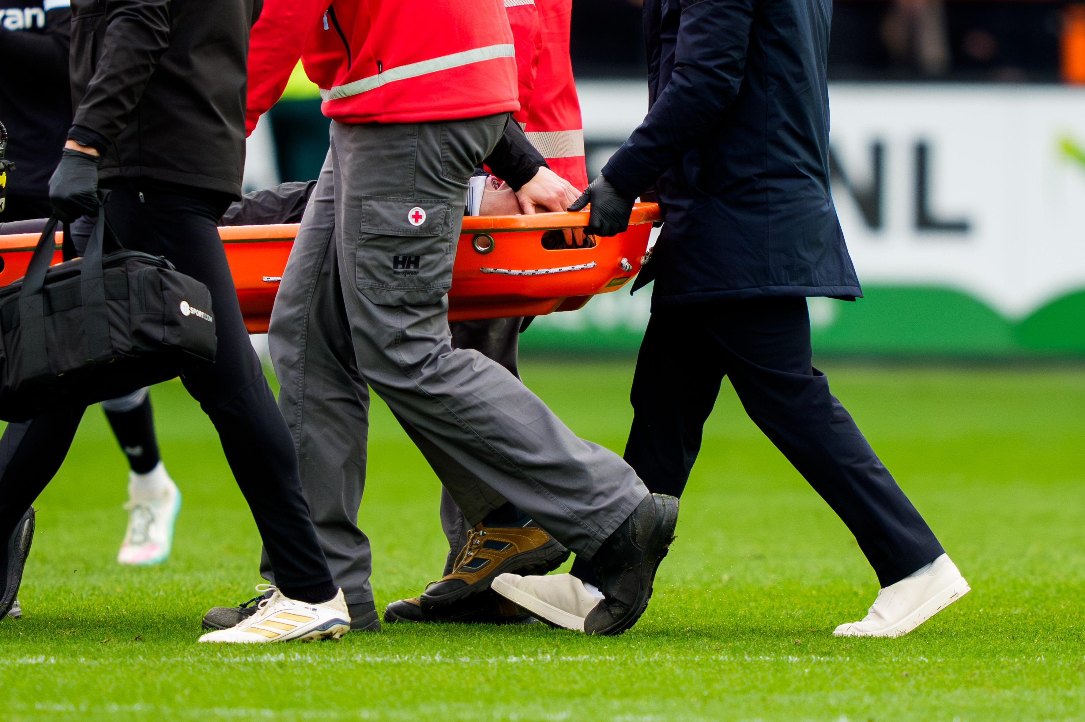 Met de handen voor het gezicht verlaat FC Groningen-aanvoerder Stije Resink zwaar geblesseerd het veld. 