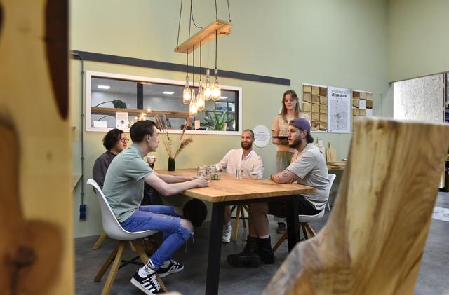 Robin Alkema (m) drinkt koffie met vanaf links Djo, voetbal-Martijn en metal-Martijn. Fleur serveert water in glazen van Pottle. Boven de tafel van Stadshout hangt een lamp die Pottle en Stadshout samen gemaakt hebben. 