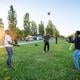 Vluchtelingen zijn aan het volleyballen op het grasveld voor het aanmeldcentrum in Ter Apel op 24 mei 2026. Op de achtergrond de bus die naar de nachtopvang in Groningen vertrekt. Foto: Huisman Media