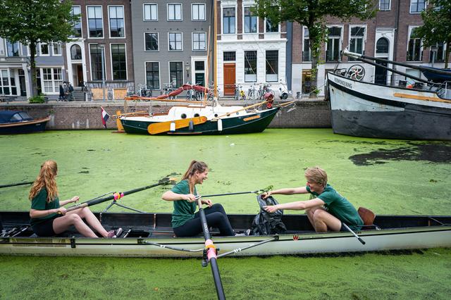 Roeiers van Gyas ruimen tijdens de KEI-week de gracht op.