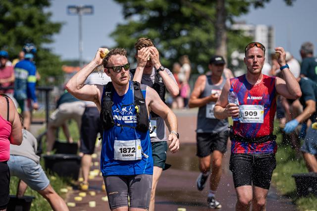 Deelnemers aan de Marathon van Groningen zoeken verkoeling met een natte spons.