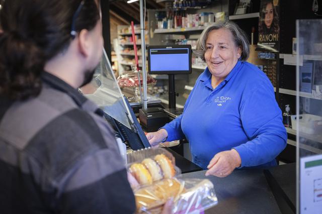 Ali Nienhuis helpt als vrijwilliger een klant bij de Dorpswinkel Sauwerd.