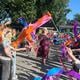 Juf Liesbeth Roelfes loopt door een kleurrijke erehaag van zwaaiende leerlingen die haar 25-jarig onderwijsjubileum vieren.