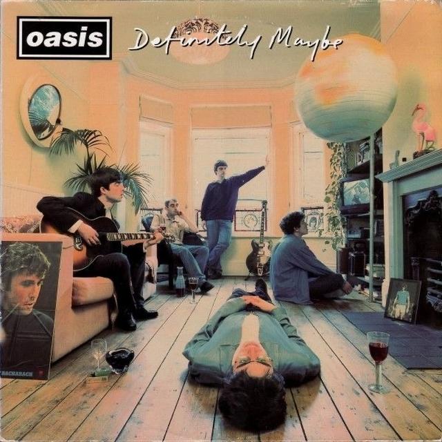 Durk-Rein Lolkema, op de voorgrond, liggend, op een foto, gemaakt in 2016 in Manchester tijdens de overzichtstentoonstelling over Oasis: ‘Chasing the sun’. De kamer is een replica van de huiskamer die op de cover van het debuutalbum 'Definitely maybe' uit 1994 staat. Deze week verscheen daarvan een speciale heruitgave, meldt Casper Ferwerda.